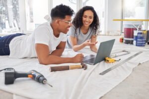 Couple on floor surrounded by tools looking at laptop considering solid core vs hollow core internal doors