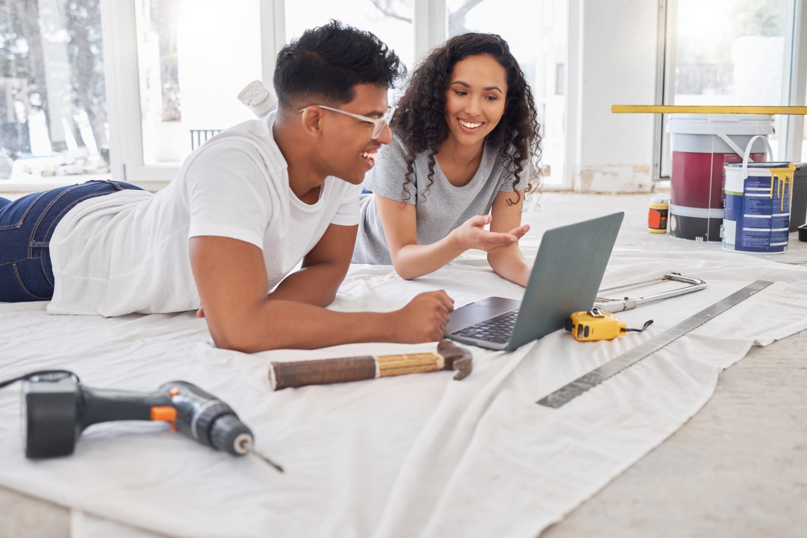 Couple on floor surrounded by tools looking at laptop considering solid core vs hollow core internal doors